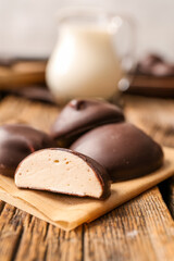 Parchment with half of tasty bird's milk candy on wooden background, closeup
