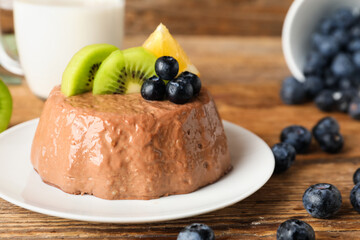 Plate with delicious chocolate pudding, blueberry, kiwi and lemon slices on wooden background
