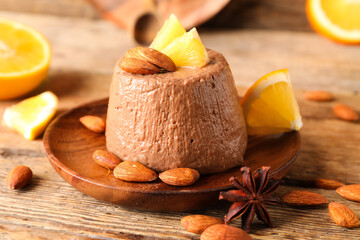 Plate with delicious chocolate pudding, almond nuts, anise and orange slices on wooden table