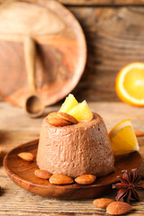 Fototapeta na wymiar Plate with delicious chocolate pudding, almond nuts, anise and orange slices on wooden table