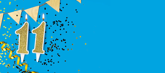 Yellow candle number 11 over blue background. Greeting card with the inscription eleventh birthday....