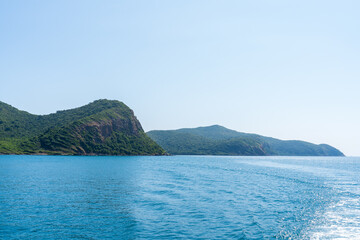 Fototapeta premium Natural landscape of green island and blue sea. Clear blue water, overlooking the wide sea, beautiful blue sea waves, Panoramic view of blue calm ocean.
