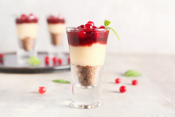 Shot of delicious pudding with cranberry, mint and jam on light table