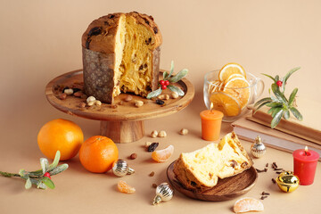 Stand with cut Panettone and Christmas decor on beige background