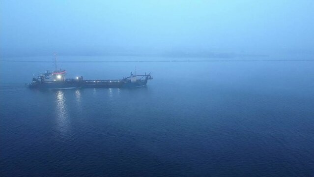 Drone view of cargo container ship sails in sea fog