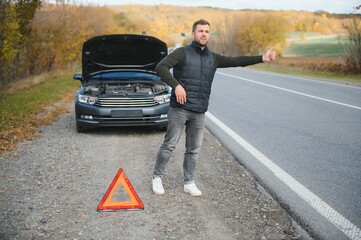 A young man with a black car that broke down on the road,copy space.