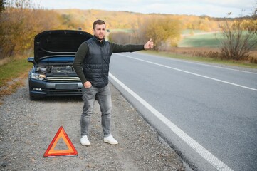 Handsome young man with his car broken down by the roadside