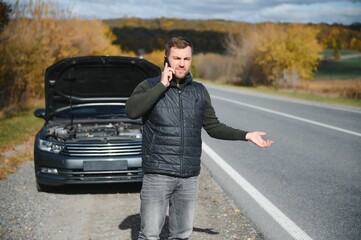 Man with broken car in the middle of the road.