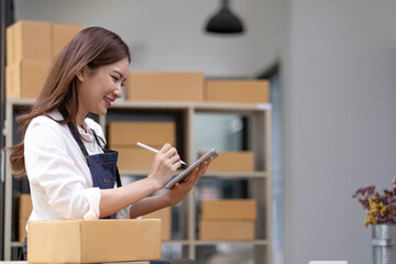 Fototapeta na wymiar Successful entrepreneur business woman with online sales and Parcel shipping in her home office, prepare parcel box of product for deliver to customer.