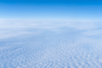 The view from the plane window of dense curly clouds and the blue stratosphere. Cloudscape. Blue sky and white cloud