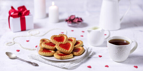 Homemade cookies in the form of hearts with red jam on Valentine's Day. On a marble table with a...