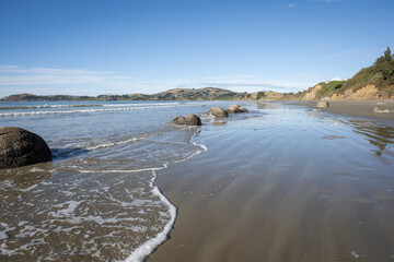 Waves splashing around the boulders at Moeraki Boulders beach, Otago.