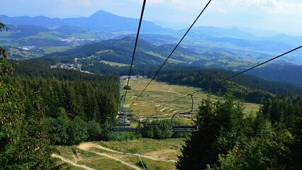 Landscape of valley with ski chairlift and downhill mtb track surrounded by coniferous forests....