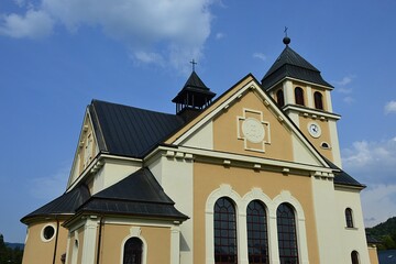 Fototapeta na wymiar Building of new catholic rectory and church of Assumption of Virgin Mary in pseudo romanesque style in Zazriva, Terchova region, northern Slovakia, during partially cloudy summer day. 