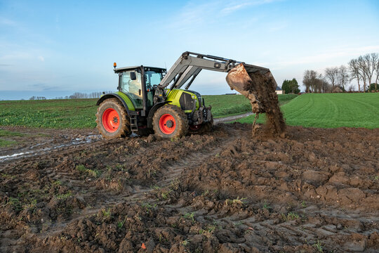Agriculteur d&eacute;gageant un chemin agricole &agrave; l'aide d'un tracteur suite &agrave; une coul&eacute;e de boue
