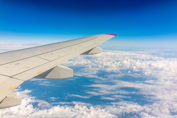 View from the airplane window at a beautiful cloudy sky and the airplane wing