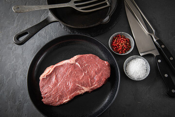 Entrecote Steak roh vom Rind mit Meersalz und roter Pfeffer auf Teller bei Vorbereitung in Küche...