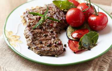 Grilled steak with tomatoes and fresh herbs. Close up. 