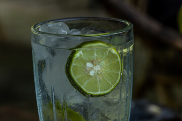 A glass of cold lemon water with ice cubes in a clear glass of glass