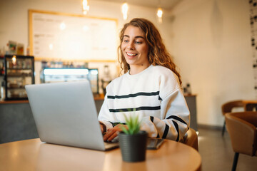 Young woman sits in a cafe and works on a computer. Business, blogging, freelance, education...