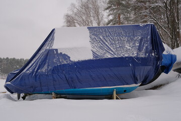 Yacht, boat, ship on the shore under a canopy awning in the snow
