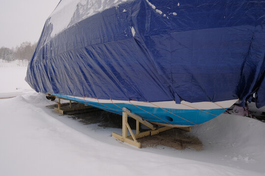 Yacht, boat, ship on the shore under a canopy awning in the snow