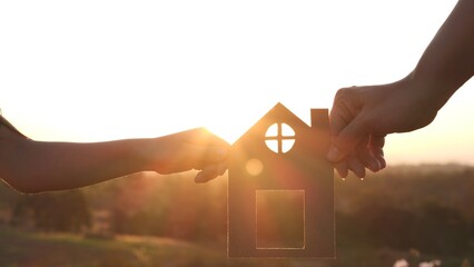 Mother and daughter hands holding paper house, home together silhouette against sunset with soft focus. Concept of Happy Family, Buy House, Home, life, insurance, care, saving, mortgage, estate
