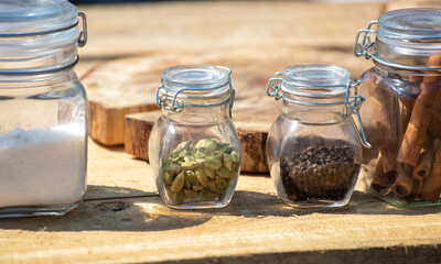 Seasonings in glass jars on a wooden table.