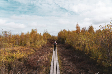 Young blonde hiker walks along a trail in Store Mosse National Park. Girl with big backpack walks...