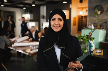 Portrait of arabic businesswoman with veil in workplace. Colleagues have a meeting.