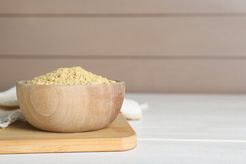 Bowl of aromatic mustard powder on white wooden table. Space for text