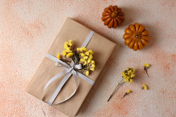 Fototapeta na wymiar Pumpkin shaped candles and book decorated with flowers on beige textured background, flat lay