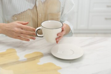 Woman with spilled coffee over her shirt at marble table indoors, closeup