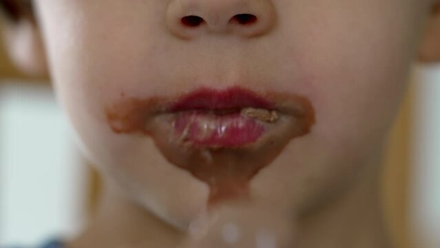 Little boy eating ice cream closeup mouth covered with chocolate. Child taking a bite of sweet dessert food