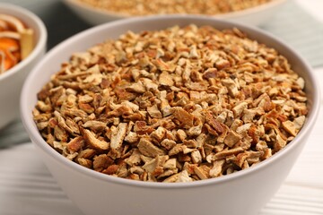 Bowl with dried orange seasoning zest on white wooden table, closeup
