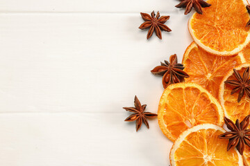 Dry orange slices and anise stars on white wooden table, flat lay. Space for text