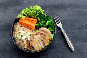 Healthy food fried rice noodle has chicken and carrot broccoli in black bowl on wood background.