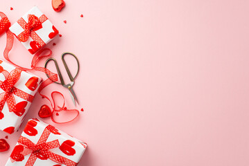 Valentine's Day concept. Top view photo of present boxes scissors tulle ribbon heart shaped candies and sprinkles on isolated light pink background with blank space