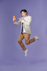 Excited casual guy pointing finger at smartphone with blank screen and jumping up