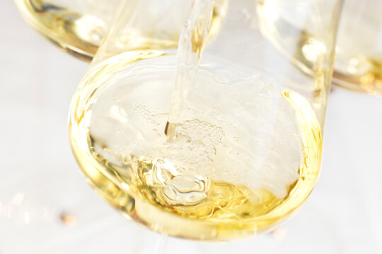 Pouring white wine in a glass with bright background