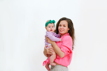 Mom gently holds a little baby girl on a white background. Festive bright clothes