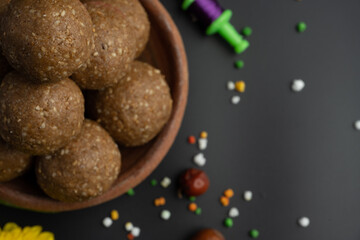 Til Gul OR Sweet Sesame Laddu with Kite model, haldi Kumkum and sugar crystals for Makar Sankranti festival over black background.