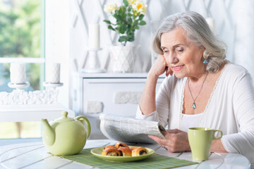  senior beautiful woman reading newspaper at home