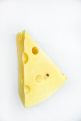 A large piece of cheese on a white background. A triangular piece of cheese with holes.