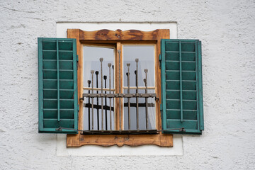 Window on the white wall facade with open green color classic shutters, Austria, closeup