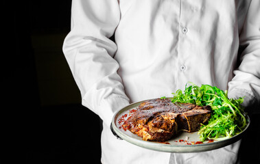 chef holding Porterhouse beef steak with salad in hand