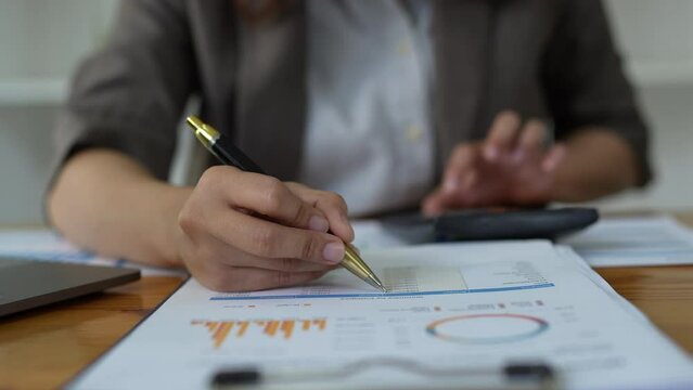 Asian Business Woman or Accountant do math and analyze with calculator and paperwork on desk, account, audit and saving concept.