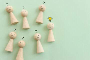 Yellow bright light bulb and question mark over pastel background with wooden figures