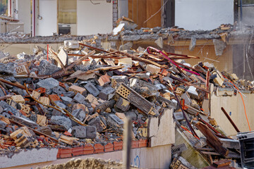 Deconstruction site with tearing down of an apartment building and heap of debris sprayed by water...