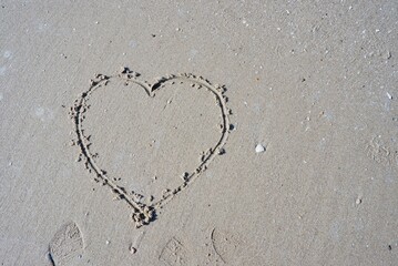 A heart sign on sea beach with shoes imported on the floor